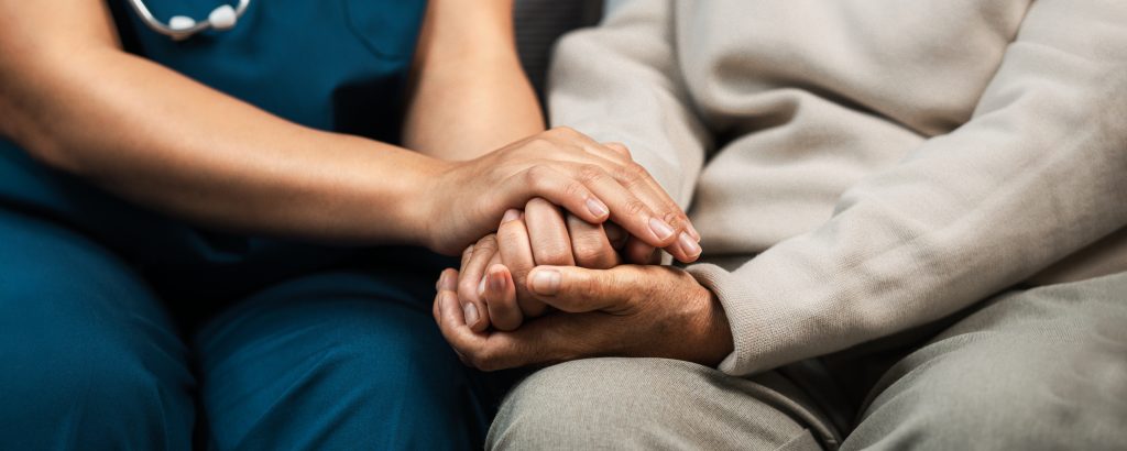 Shows whole-person care in action with Nurse praying with Elderly patient