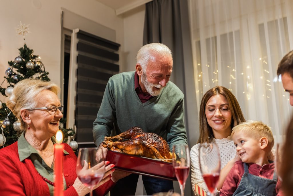 Family gathered for Thanksgiving dinner, bowing in prayer as they talk about faith and gratitude.